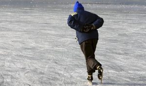 Ældre mand står på skøjter, på en skøjtebane